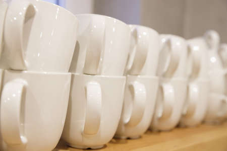 lots of white clean coffee cups after washing in the dishwasher stand in a row. selective focus.High...