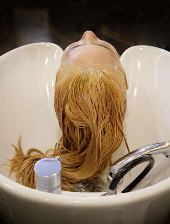 Beautiful young woman with hairdresser washing her head in a hair salon. High quality photoの写真素材