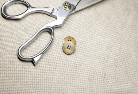 tailors scissors lie on a burlap close-up and wooden buttons. selective focus.High quality photo