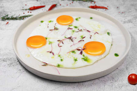 Breakfast. fried eggs from three eggs are sprinkled with grass on a light plate. . High quality photoの写真素材