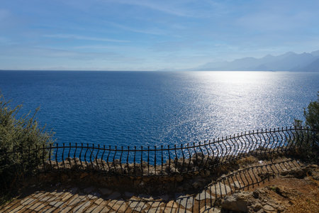 sea view from the stone shore with a wrought iron fence. solar glare on shallow waves. coast. free space for your text. High quality photoの写真素材