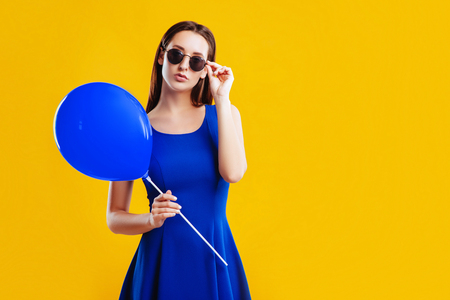Young woman with air balloon over yellow backgroundの写真素材