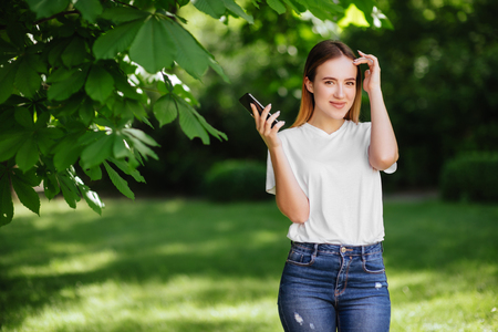 Girl with phone in park.の写真素材
