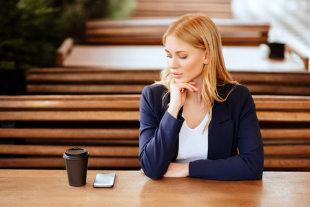 Beautiful woman drinking coffee in a cafe and phoneの写真素材