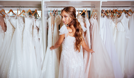 Attractive young bride is smiling while choosing wedding dressの写真素材