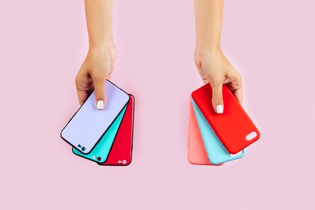 hands holding colorful smartphone cases. Pink Backgroundの写真素材