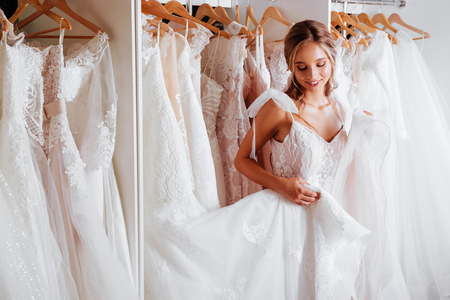 Attractive young bride is smiling while choosing wedding dressの写真素材