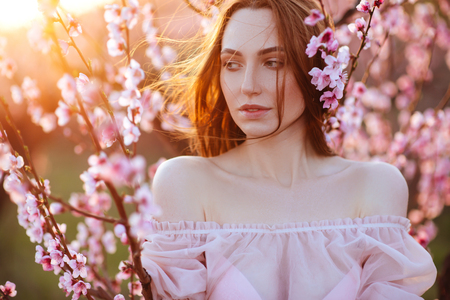 Beautiful young girl under the flowering pink treeの写真素材