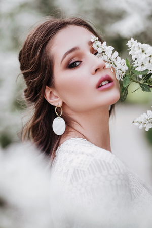 A beautiful young girl stands among the flowering trees.の写真素材