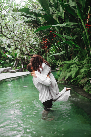 Happy couple kissing while relaxing in outdoor spa swimming poolの写真素材