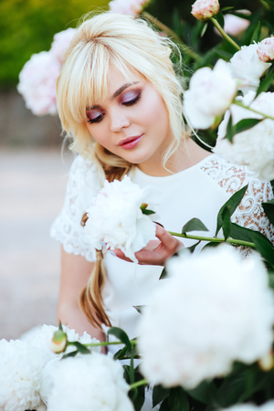 Outdoor close up portrait of beautiful young woman in the blooming garden. Female spring fashion conceptの写真素材