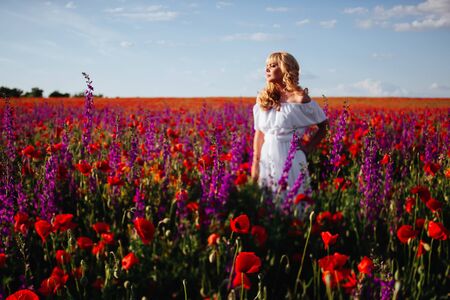 cheerful girl with curly blond hair in a huge poppy field alone,の写真素材