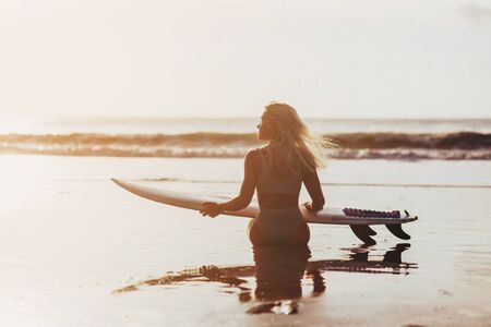 Beautiful sexy surfer girl on the beach at sunsetの写真素材