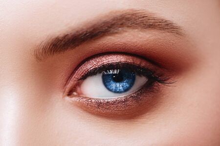 Close up view of blue woman eye with beautiful golden shades and black eyeliner makeup.の写真素材