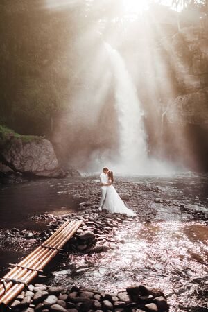 Young couple in love bride and groom, wedding day near a mountain waterfall.の写真素材