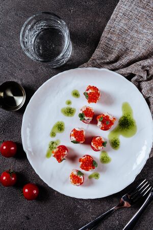 Three stuffed tomatoes and delicious healthy appetizer on a white plateの写真素材