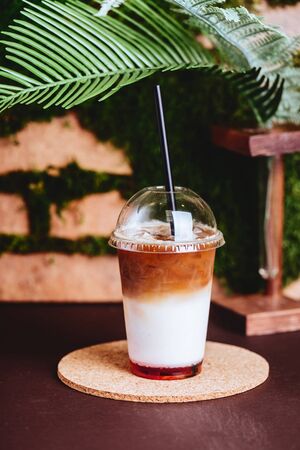 Smoothies and iced coffee in plastic cup on wooden tray and brick wall background in cafe.の写真素材