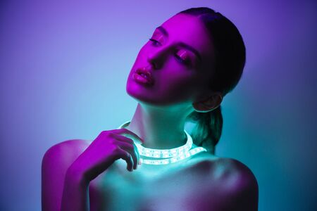 High Fashion model girl in neon lights posing in studio, portrait of beautiful woman, trendy glowing...