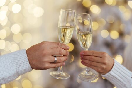 Close up photo of two people holding glasses of shampagne on xmasの写真素材