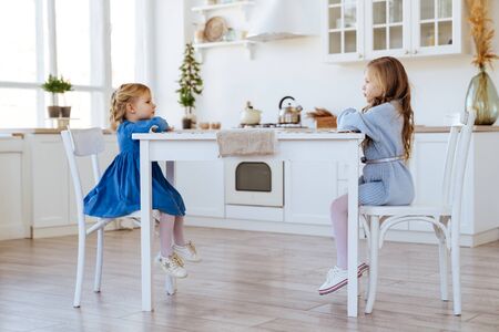 two children sitting on the kitchen table.の写真素材