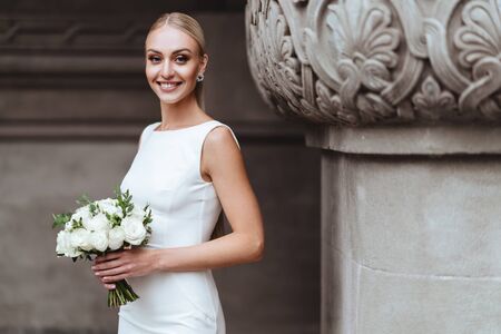 Beautiful stylish blonde bride posing near old castle wallの写真素材