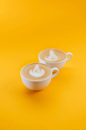 two cups of Latte coffee on yellow background.の写真素材