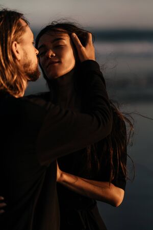 Attractive man and woman enjoying romantic evening on sunsetの写真素材
