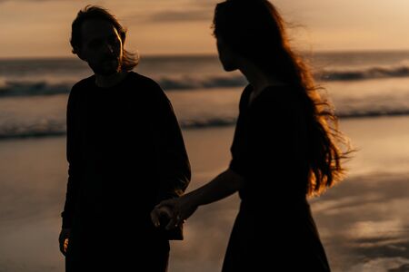 Attractive man and woman enjoying romantic evening on sunsetの写真素材