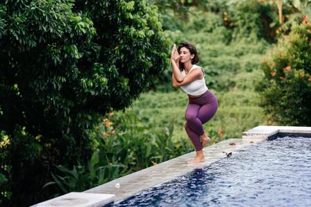 Woman practicing yoga performing yoga-asanas outdoors.