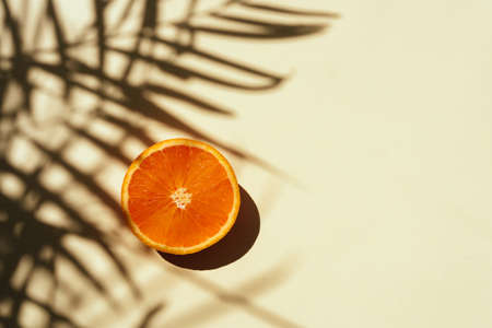 Summer tropical composition. Shadow of palm leaves and tropical fruits on pastel yellow background.の写真素材