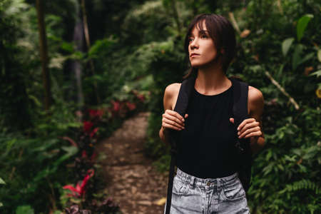 Traveler woman with backpack walking on path in jungle tropical deep forest,の写真素材
