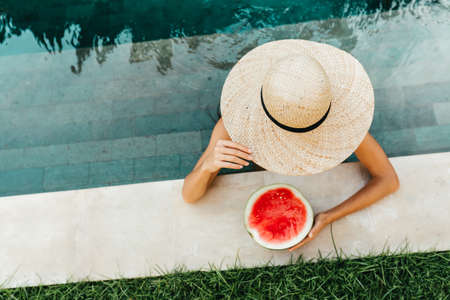 Girl holding watermelon in the blue pool, slim legsの写真素材