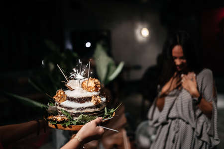 Portrait of charming girl blowing on candles on birthday cakeの写真素材