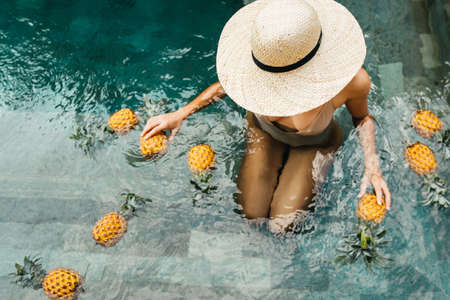 Beautiful Woman Relaxing In Swimming Pool With Pineapples. Healthy Lifestyle, Nutrition, Diet. Summer Vacationの写真素材