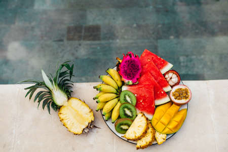 Still life image of tropical fruits and flowers near the pool