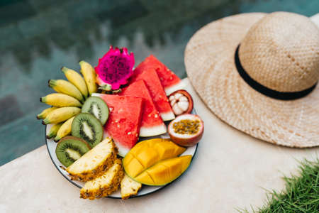 Still life image of tropical fruits and flowers near the pool