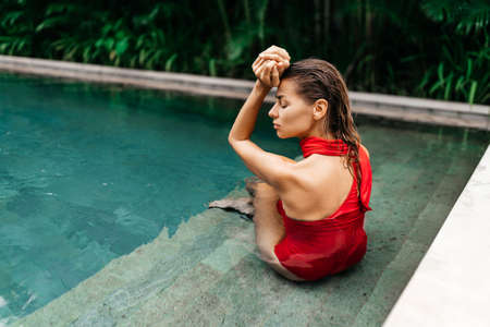 woman in red swimsuit relaxing in swimming poolの写真素材