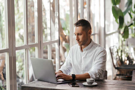 young man working on his computer at the cafeの写真素材