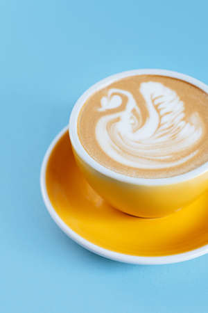 Yellow cup on blue wooden backgroundの写真素材