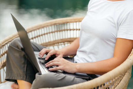 Young woman near swimming pool and working at latop computer