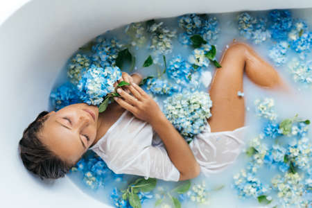 Woman relaxing in bath with tropical blue hydrangea.の写真素材