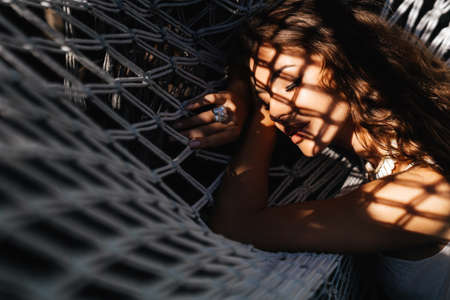 Attractive young woman is relaxing outdoor while lying in hammock.