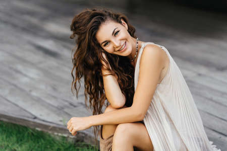 Photo of beautiful lady in white dress sitting on the wooden floor,summer accessories.の写真素材