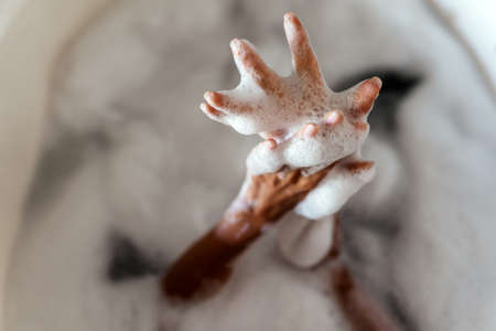 A young women hands while laying in bathtub
