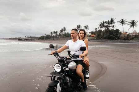 Young couple riding motorcycle on the beachの写真素材