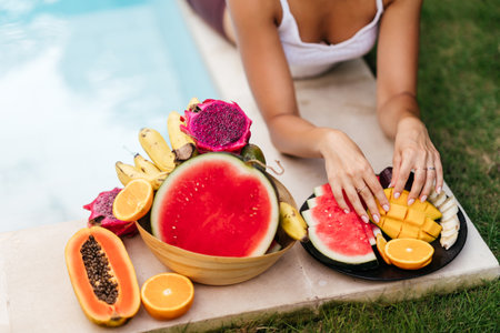 Woman relaxing and eating fruits in the pool on luxury villa in Bali.の写真素材