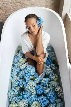 Woman relaxing in bath with tropical blue hydrangea.の写真素材
