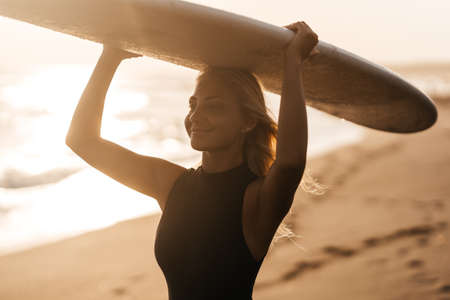 Beautiful surfer woman on the beach at sunsetの写真素材