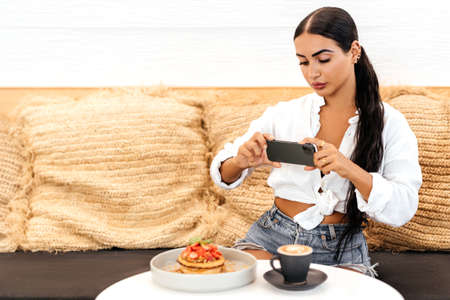 Woman taking a photo of breakfast with smartphoneの写真素材