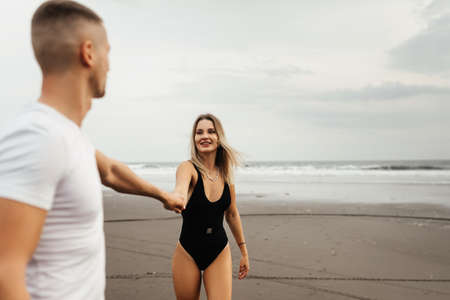 Outdoor shot of smiling young couple walking on beach.の写真素材